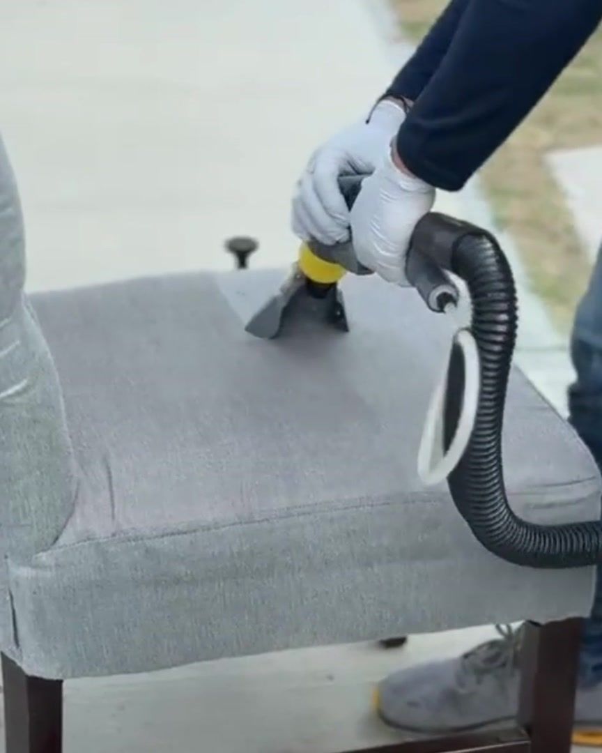 Boquilla de inyección-succión sobre el asiento de una silla de tela gris durante un lavado profundo